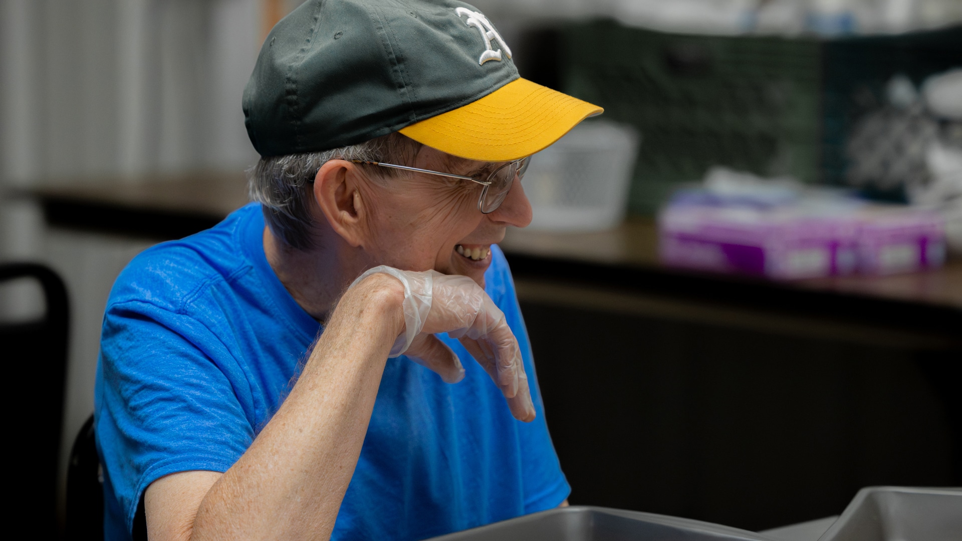 A CARC resident smiling and shelling pecans by hand.