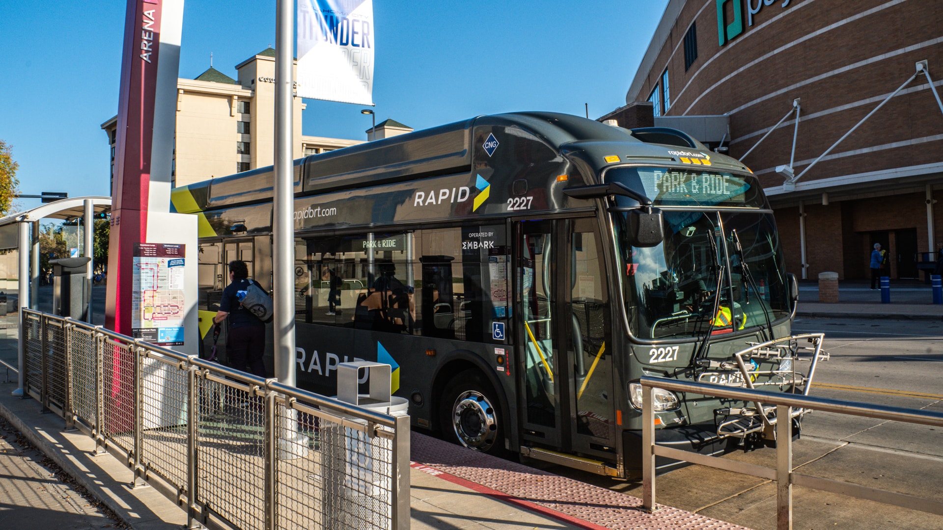 An EMBARK RAPID rebranded bus stopping at a bus stop.